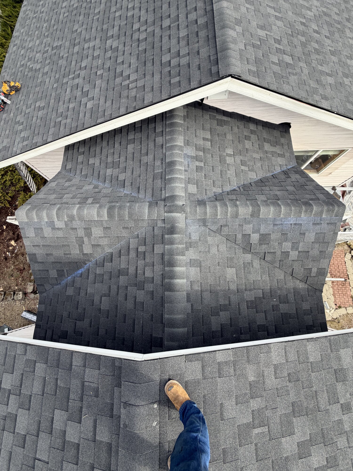 Aerial view of a completed asphalt shingle roof with multiple hips and valleys